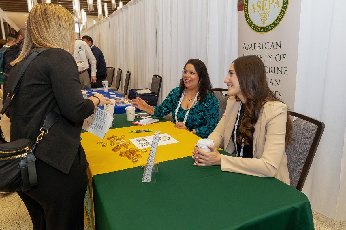Attendees talking to a non-profit representative at table. 