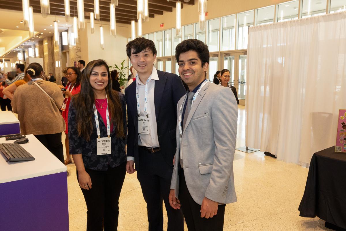 Three attendees standing together and smiling for photo. 