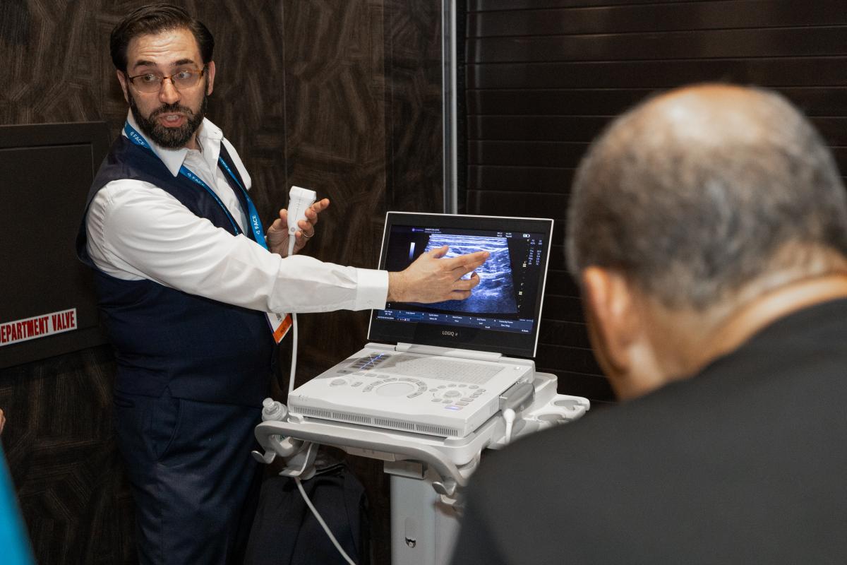 Photo of instructor working with an ultrasound machine with a group of attendees watching.  