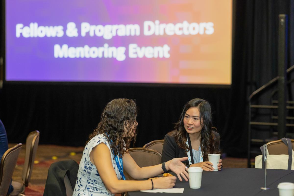 Two attendees talking in a meeting room. 
